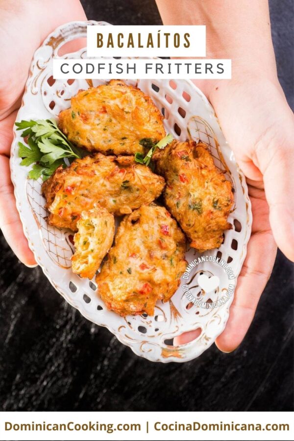 Holding a plate full of the Bacalaítos (codfish fritters)