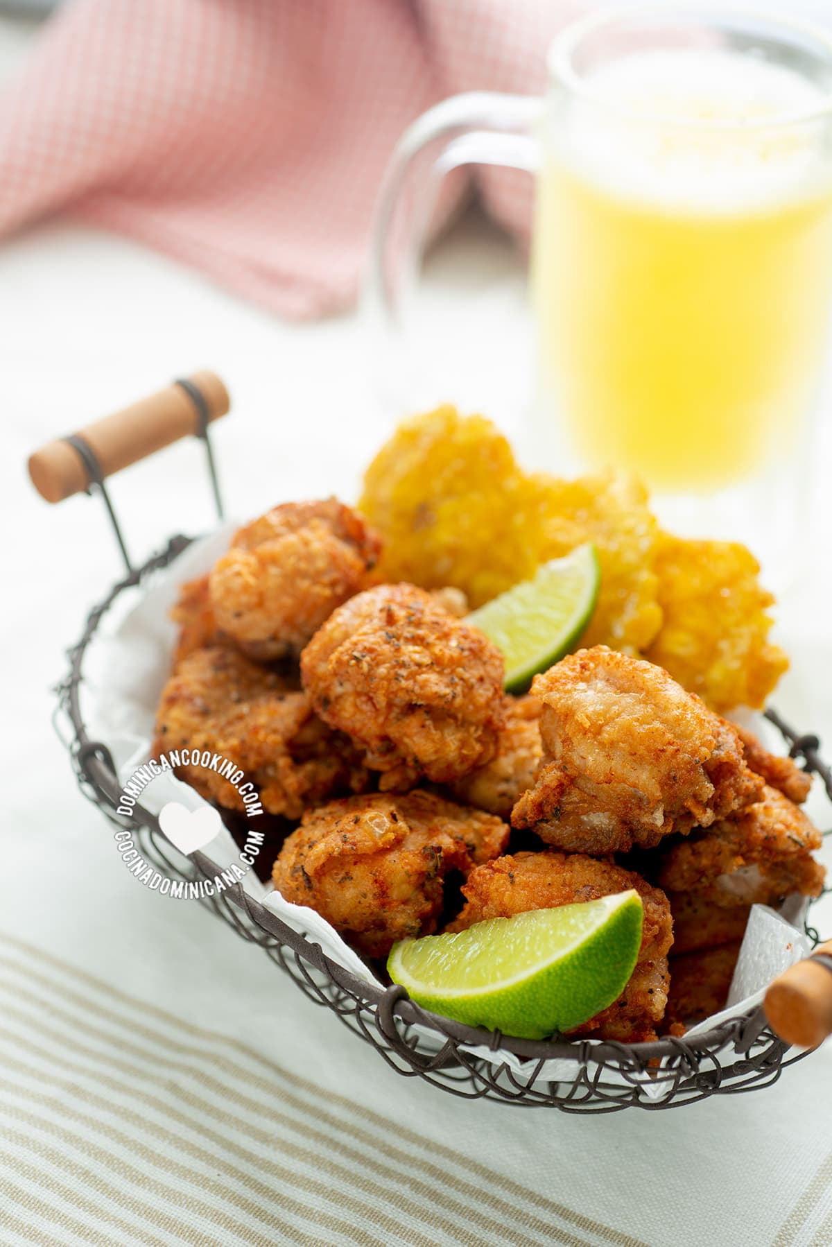 Chicharron de pollo served with tostones and lime wedges.