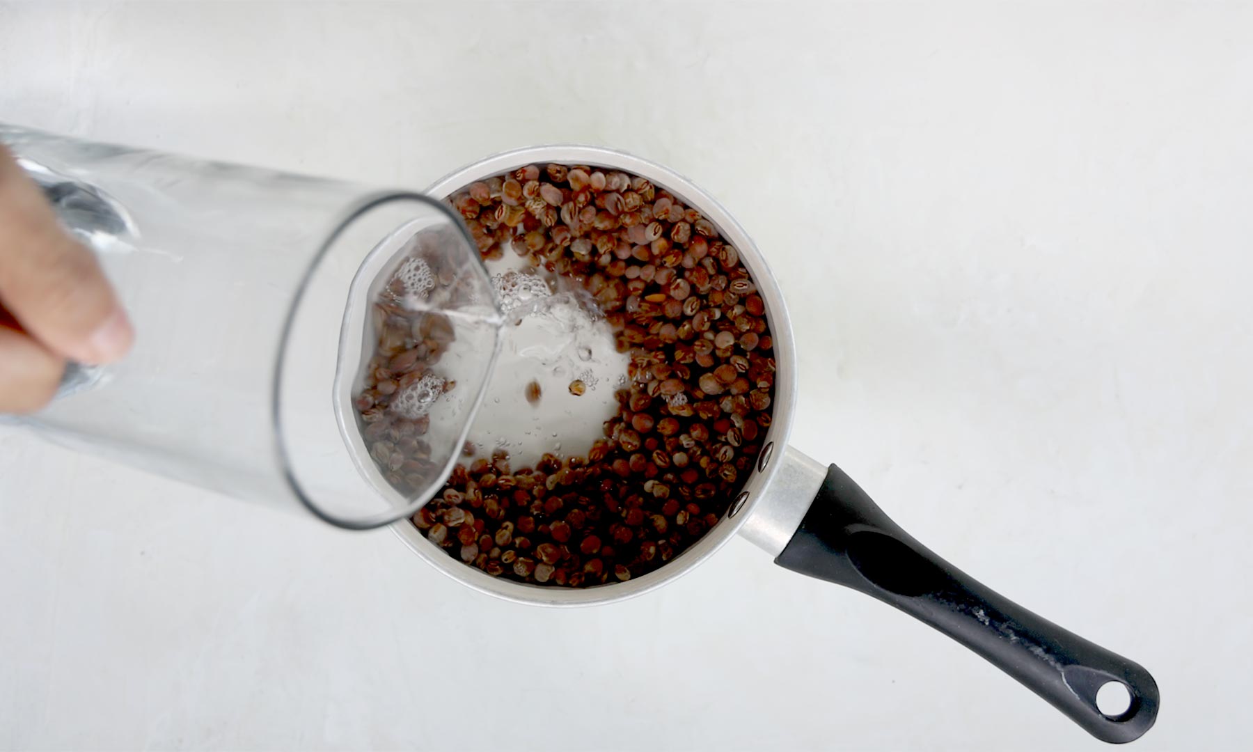 Adding water to pot with guandules.