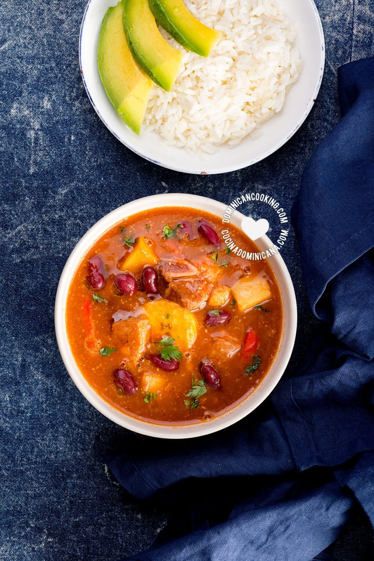 Bowl of sancocho de habichuelas or sopi&oacute;n or zambumbio  (sweet & spicy bean stew) served with rice and avocado slices.